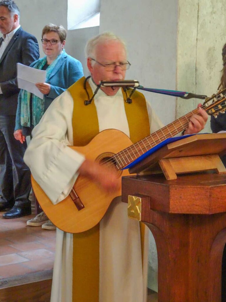 Pilgerleiter Bruno Oegerli mit Gitarre und Mundharmonika bei der Andacht in der Ranftkapelle. | © 2022 Kurt Kaelin